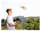 Un adolescent pilote un drone orange et sa télécommande.