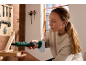 Femme utilisant une clé à cliquet sans fil sur une étagère en bois, outils en arrière-plan.
