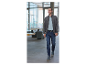 Un homme marche à l'intérieur en portant une veste, un polo et un jean.