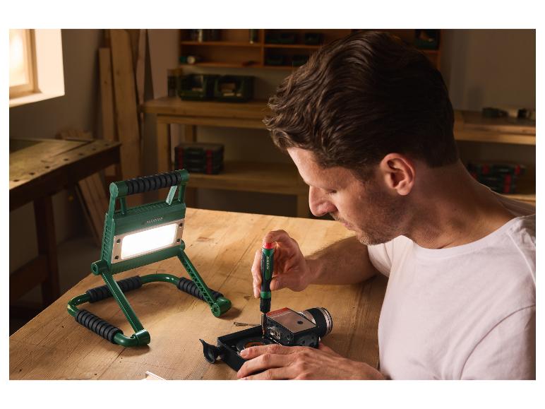 Homme travaillant dans un atelier éclairé par le projecteur LED PARKSIDE.
