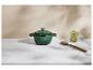Cocotte en fonte verte, cuillère en bois et pot de feuilles de laurier sur un comptoir en marbre.