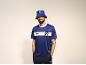 Homme en maillot de sport bleu avec bande blanche et bob assorti.