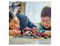 Deux personnes jouent avec un set LEGO Speed Champions, une voiture de course et un arrêt au stand.