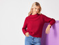 Une femme avec un pull rouge et un jean bleu.