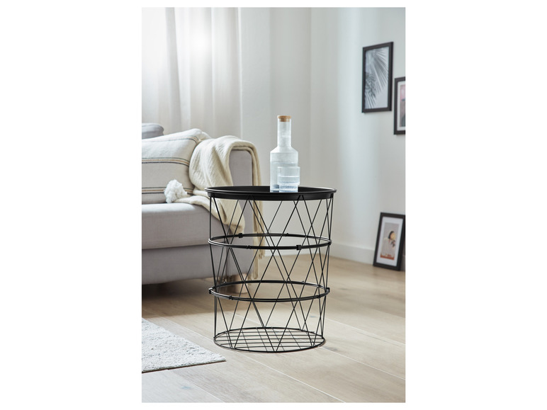 Une table d'appoint en métal noir avec une carafe en verre et un verre