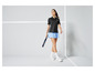Une femme portant un polo noir et une jupe bleue tenant une raquette de paddle.