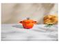 Cocotte en fonte émaillée orange sur un comptoir en marbre avec une planche à découper en bois et de la ciboulette.