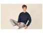 Garçon en sweat-shirt bleu marine et pantalon de jogging gris, assis sur un tabouret blanc.