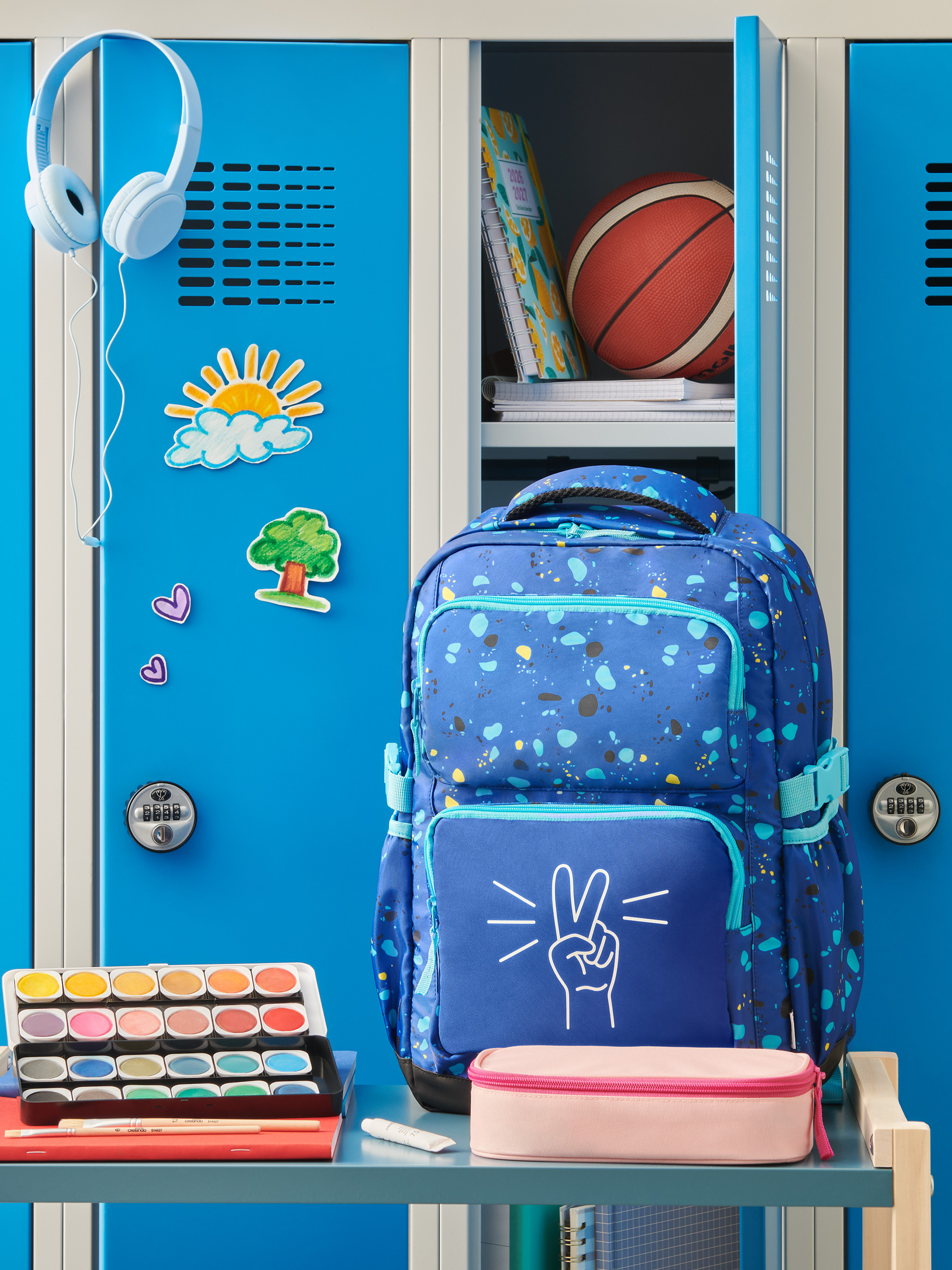 Sac à dos bleu avec signe de paix, écouteurs, aquarelles et fournitures scolaires dans un casier.