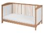 Un lit bébé en bois avec un matelas blanc.