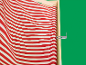 Tissu rayé rouge et blanc d'une chaise longue sur fond vert.