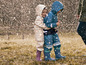 Deux enfants en vêtements de pluie et bottes jouent sous la pluie.