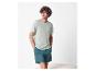 Un homme porte un t-shirt vert clair et un short vert foncé.