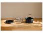 Plat rond, grille et pot avec poignée pour friteuse à air sur une table en bois.