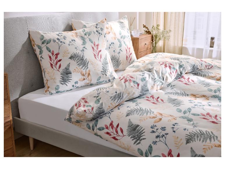 Lit avec parure de lit blanche à motif de feuilles et tête de lit grise.