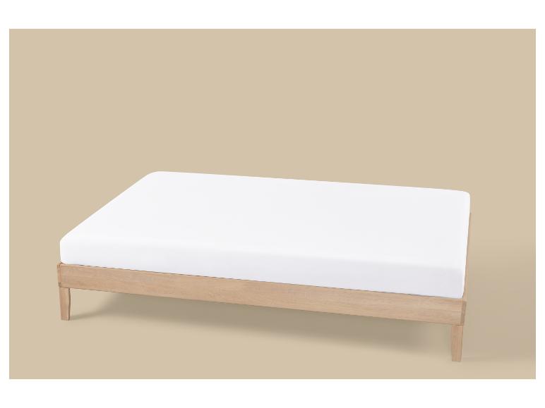 Cadre de lit en bois clair avec un matelas blanc sur fond beige.