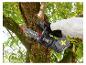 Une personne utilise une tronçonneuse sans fil Parkside pour couper une branche d'arbre.