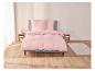 Une parure de lit rose sur un lit avec deux oreillers.