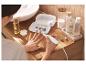 Femme utilisant un set électrique de manucure et pédicure, avec des produits de beauté à proximité.