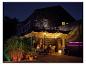 Personnes dînant sur une terrasse avec éclairage LED coloré et barbecue.