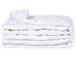 Couette blanche pliée avec bords en maille et design matelassé.