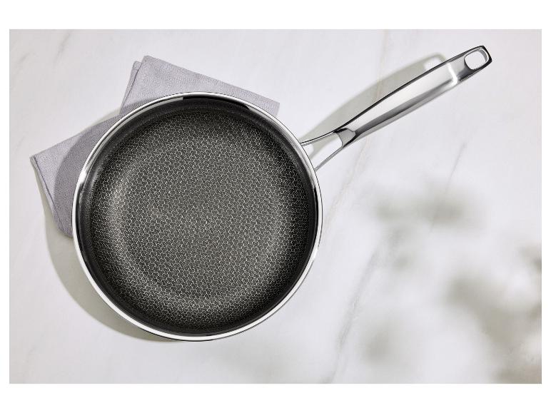 Poêle avec motif nid d'abeille sur un torchon gris sur une surface en marbre blanc.