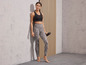 Femme portant un soutien-gorge de sport noir et un legging rayé avec une bouteille d'eau.