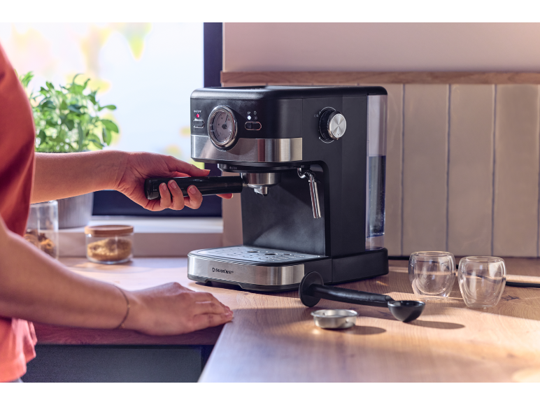 Personne fixant le porte-filtre à une machine à expresso sur un comptoir.