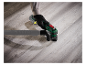 Une main gantée utilise une ponceuse Festool pour polir un sol en bois.