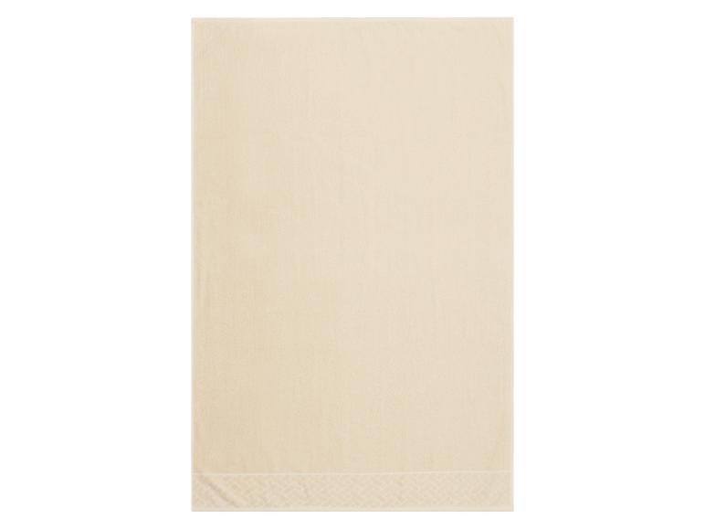 Serviette de bain beige avec motif décoratif sur la bordure