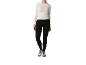 Femme en t-shirt blanc à manches longues et leggings de sport noirs avec des baskets.
