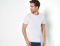 Un homme porte un t-shirt blanc et un jean bleu.