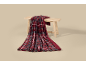 Plaid écossais rouge et gris avec doublure sherpa, élégamment drapé sur un banc en bois.
