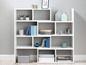 Une étagère blanche avec des livres, des plantes, des objets décoratifs et un arrosoir.