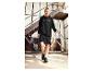 Une femme portant une robe sweat-shirt noire et des baskets Puma porte un tapis de yoga.