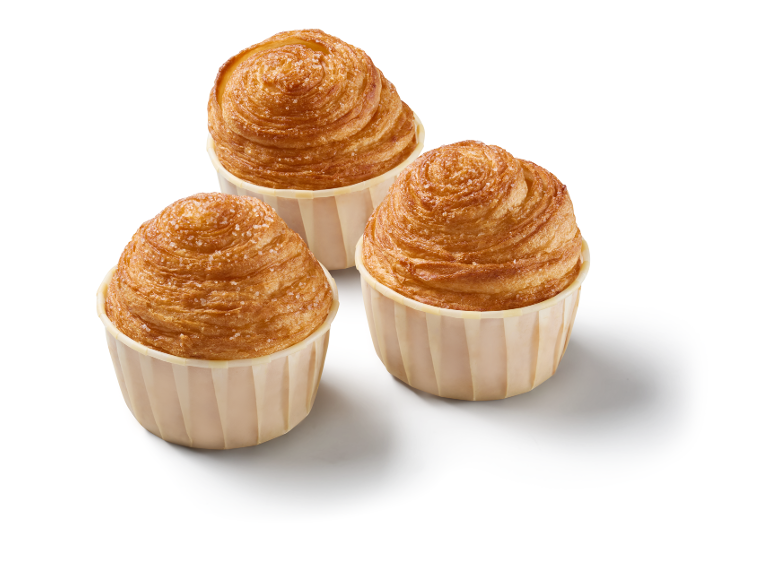 Trois pâtisseries dorées saupoudrées de sucre dans des caissettes en papier sur fond blanc.