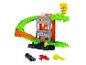 Circuit de voitures jouets avec un alligator vert, un bâtiment et un panneau de pizza, avec trois voitures jouets.