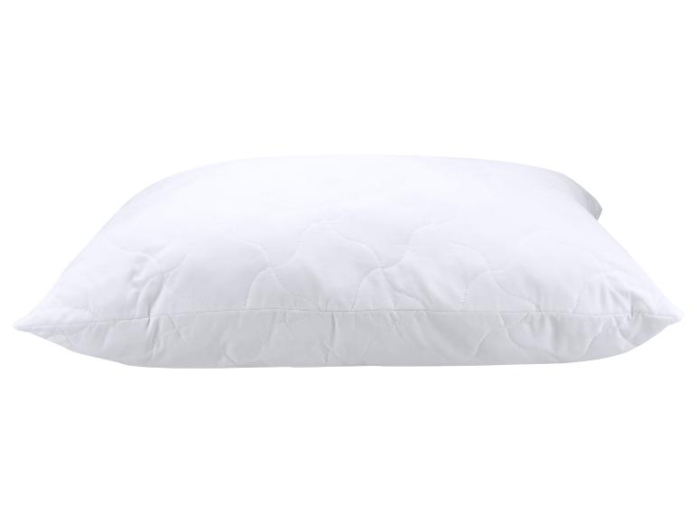 Oreiller blanc matelassé avec un motif ondulé.