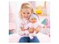 Petite fille souriante tenant une poupée bébé en tenue rose et bonnet gris.