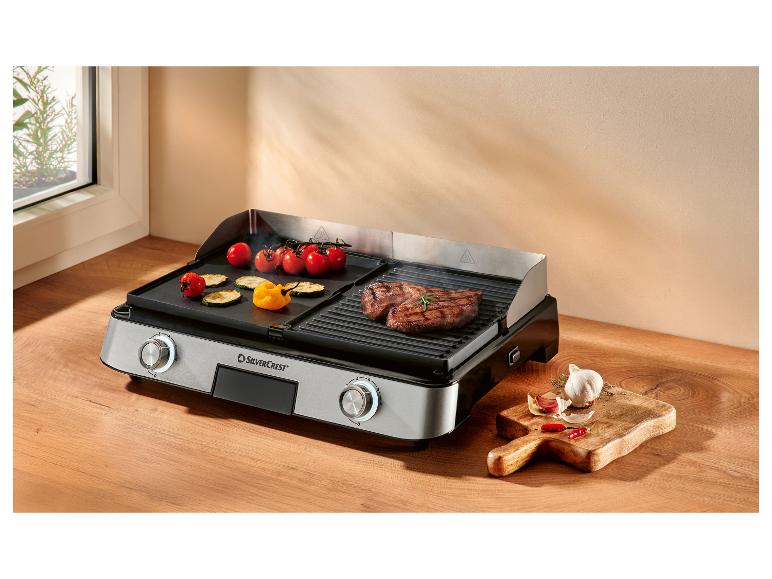 Grill électrique avec viande et légumes grillés, avec ail et piments sur le côté.