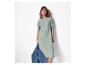 Femme portant une robe pull vert clair et tenant une veste en jean.