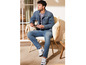 Un homme en jean et veste en jean assis sur un fauteuil en osier.