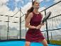 Femme en robe de sport avec raquette de padel sur un court extérieur.