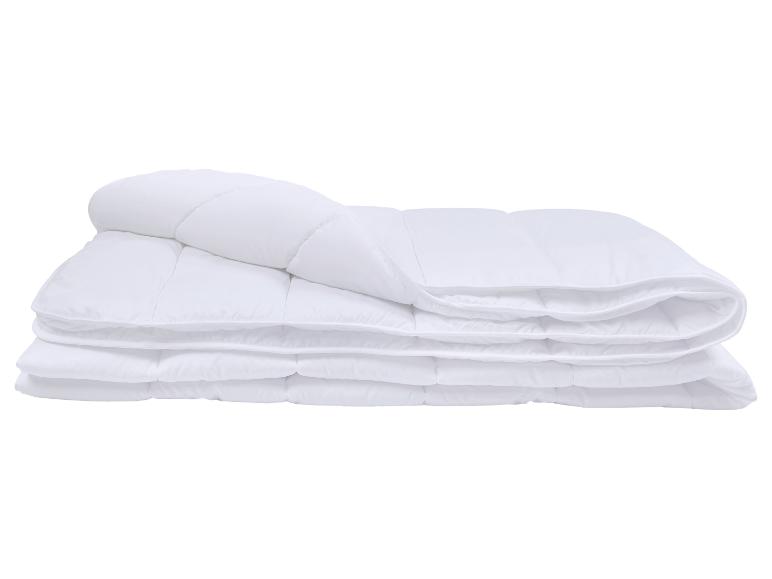 Couette blanche matelassée pliée sur fond blanc.