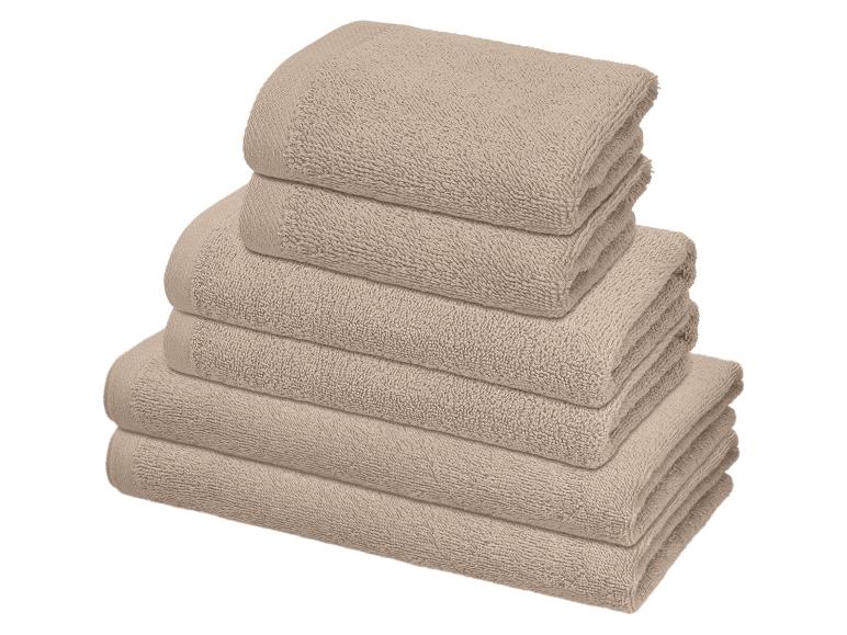 Pile de six serviettes couleur sable, soigneusement pliées et empilées les unes sur les autres.
