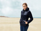 Une femme porte une veste matelassée noire avec une ceinture sur la plage.