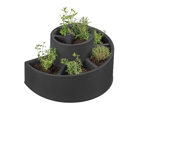 Un pot à herbes noir avec différentes herbes, y compris la menthe, le romarin et le thym.