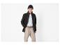 Homme en veste polaire noire, t-shirt blanc, pantalon beige et bonnet noir.