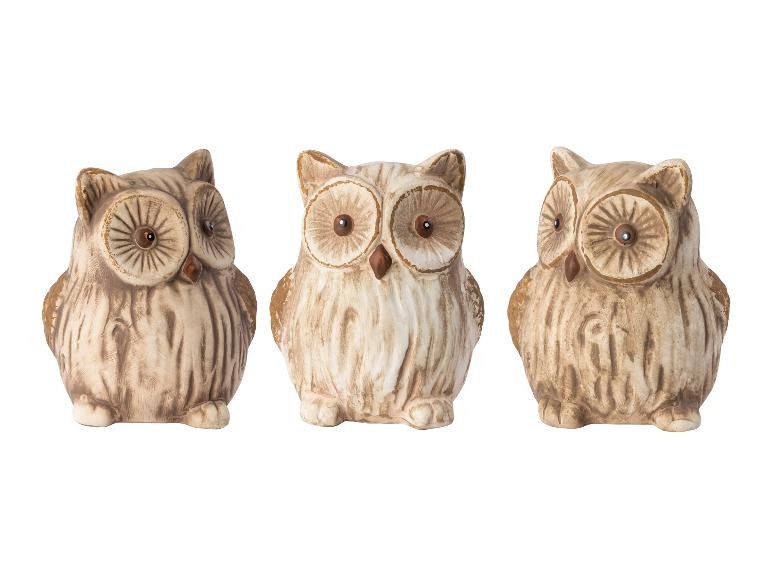 Trois statuettes de chouettes en céramique, dans les tons brun et blanc.
