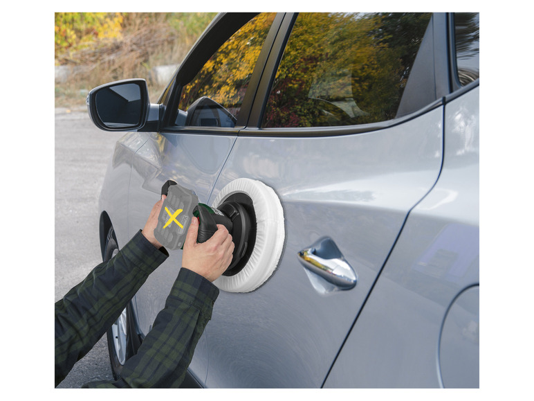 Une personne utilise une polisseuse pour faire briller la peinture d'une voiture.